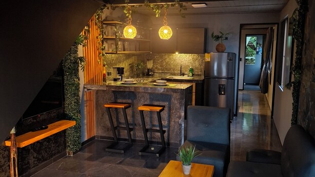 A modern kitchen with a central island, bar stools, and pendant lighting. - Loft authentic coffee axis (Risaralda)