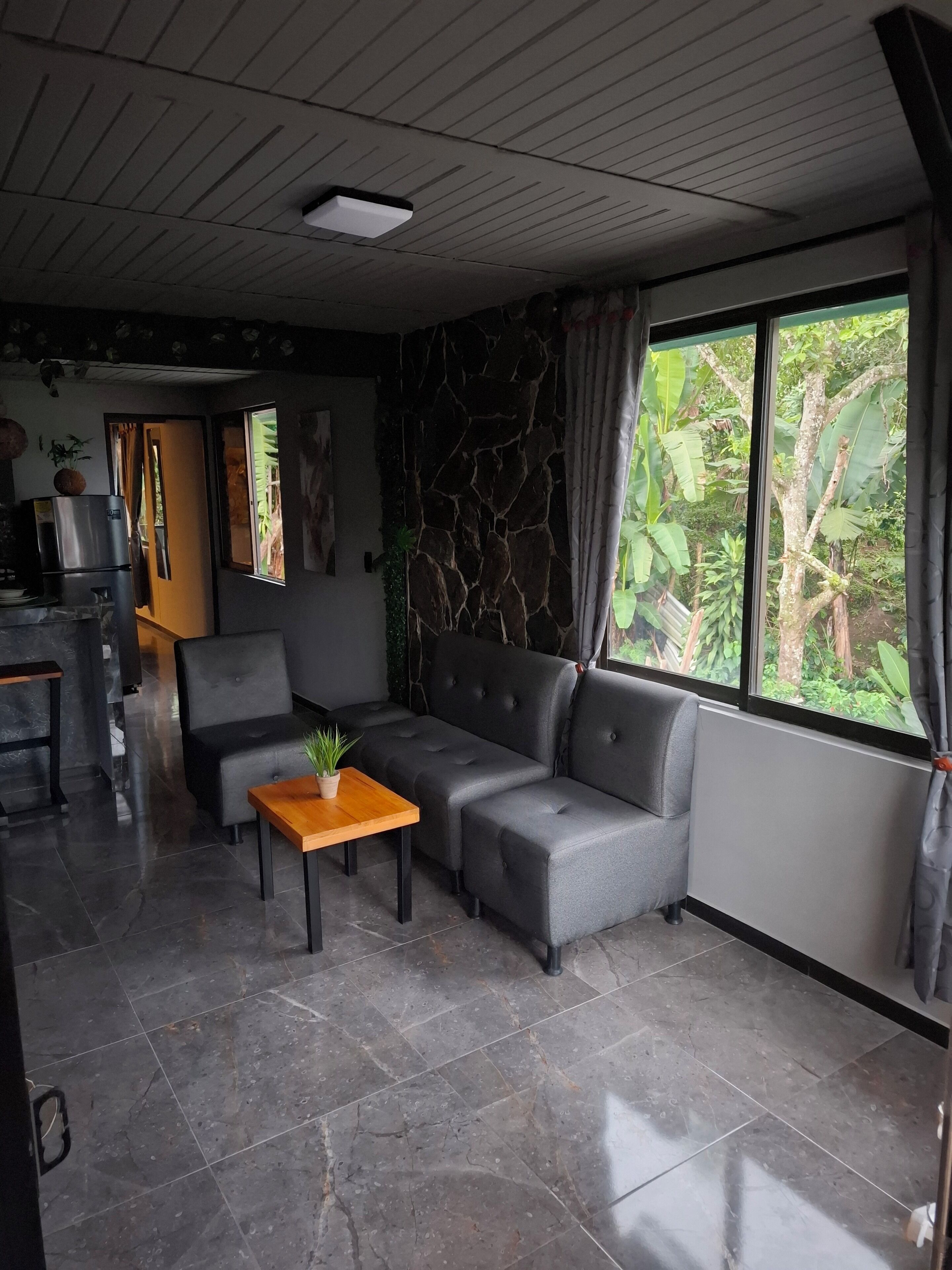 A modern living room with a grey sectional sofa, a wooden coffee table, and a stone accent wall.
