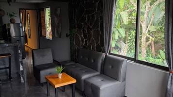 A modern living room with a grey sectional sofa, a wooden coffee table, and a stone accent wall.