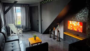 A modern living room with a fireplace, a TV, a sofa, a coffee table, and a chair. - Loft authentic coffee axis (Risaralda)