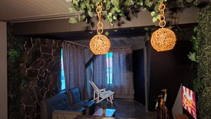 A modern lounge area with stone walls, blue seating, and a dining table set with plates and leaves. - Loft authentic coffee axis (Risaralda)