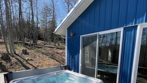 Un jacuzzi en una terraza de madera con un edificio azul al fondo.