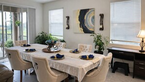 A dining area with a table set for four, chairs, a potted plant, and a painting on the wall. - 2 BR Condo w/ Private Pool & Jacuzzi · Solterra Resort · 15 min to Disney Area (Davenport)