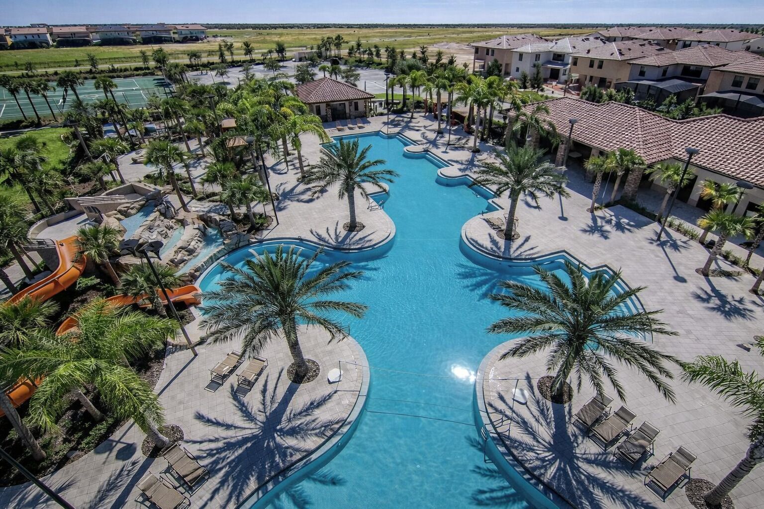 Ein Resort mit einem zentralen Swimmingpool, Palmen und Blick auf die umliegende Landschaft.
