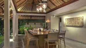 Een eetruimte met een lange houten tafel, gedekt voor zes personen, omringd door rieten stoelen.