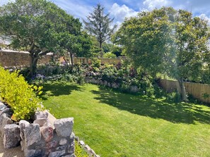Ein gepflegter Garten mit einer Steinmauer, verschiedenen Pflanzen und einem Holzzaun.