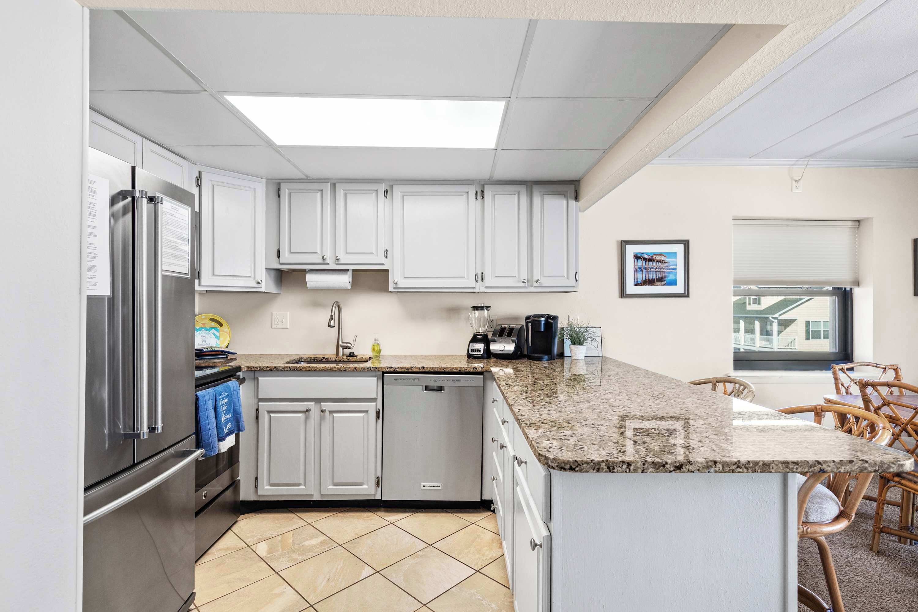 A modern kitchen with white cabinets, a granite countertop, and a built-in dishwasher.