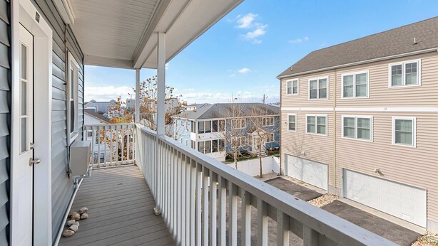 A residential building with a covered porch, a garage, and a view of neighboring houses. - Harbor Breeze #68 (Ocean City)