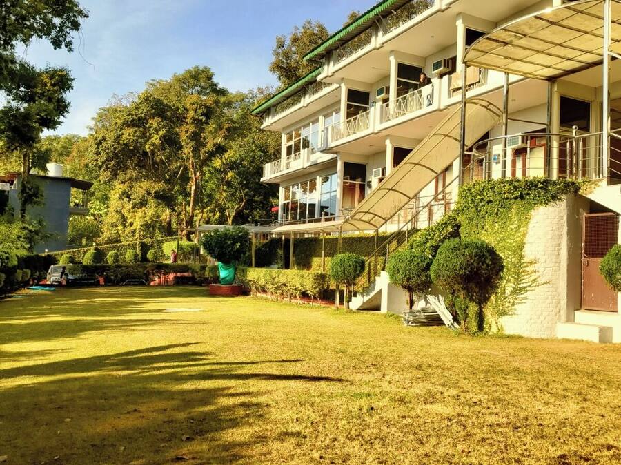 Un edificio de varios pisos con balcones, una escalera cubierta y un césped bien cuidado.