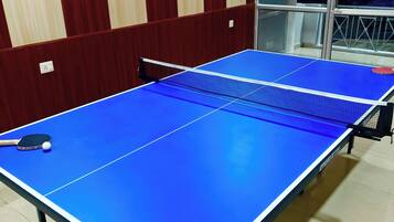 Una mesa de ping pong con red en una habitación con paneles de madera y una ventana.