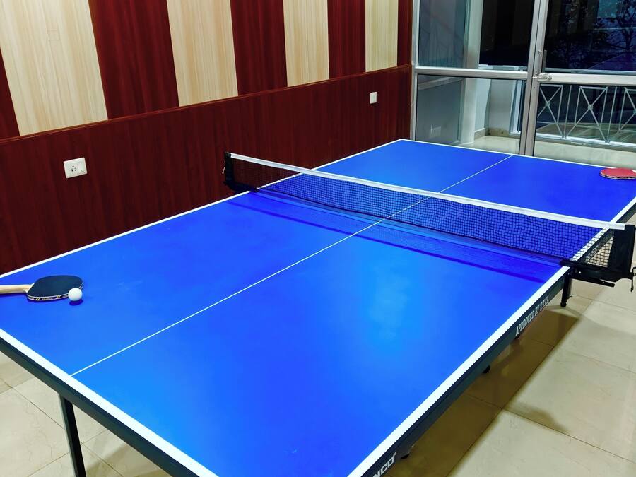 Una mesa de ping pong con red en una habitación con paneles de madera y una ventana.