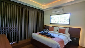 A hotel room with a large bed, a desk, a window with a view, and an air conditioning unit. - Semu Villa (Pemenang)