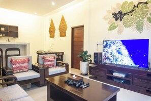 A living room with a TV, seating, and a decorative wall. - Semu Villa (Pemenang)