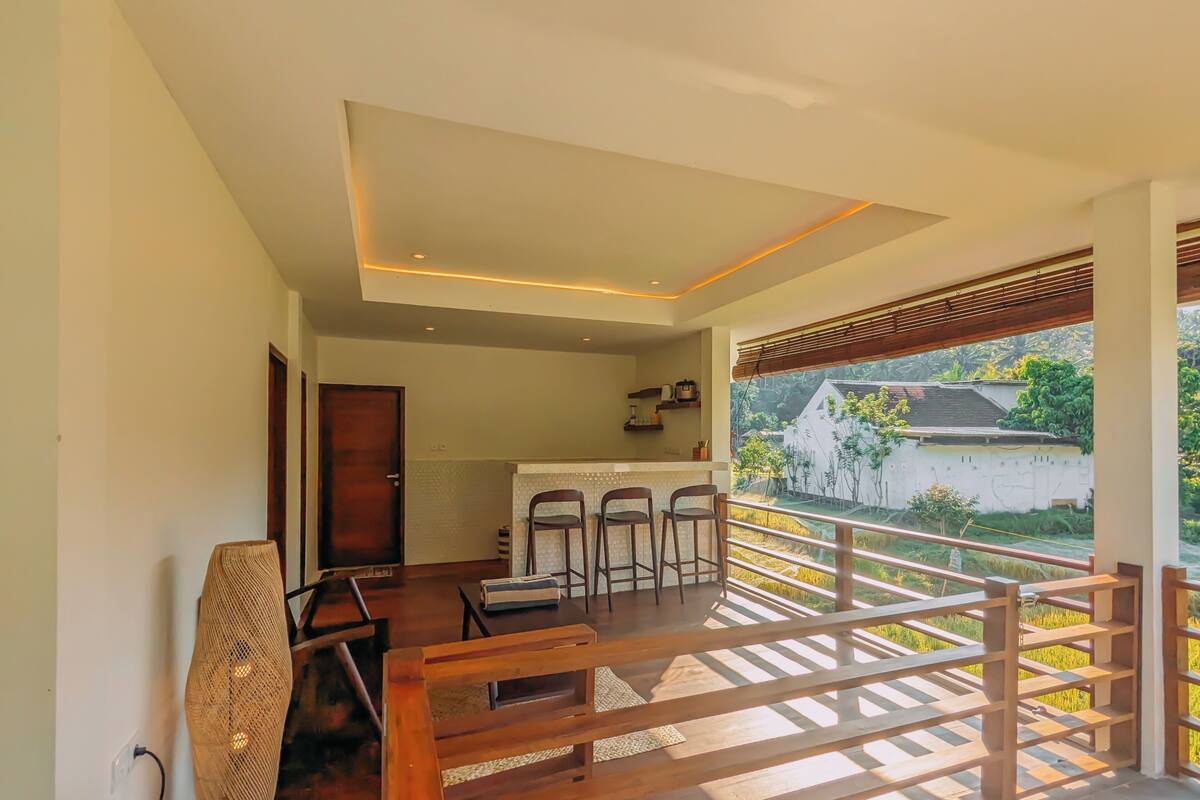 A modern interior with a dining area, kitchen, and a balcony with a view of greenery.