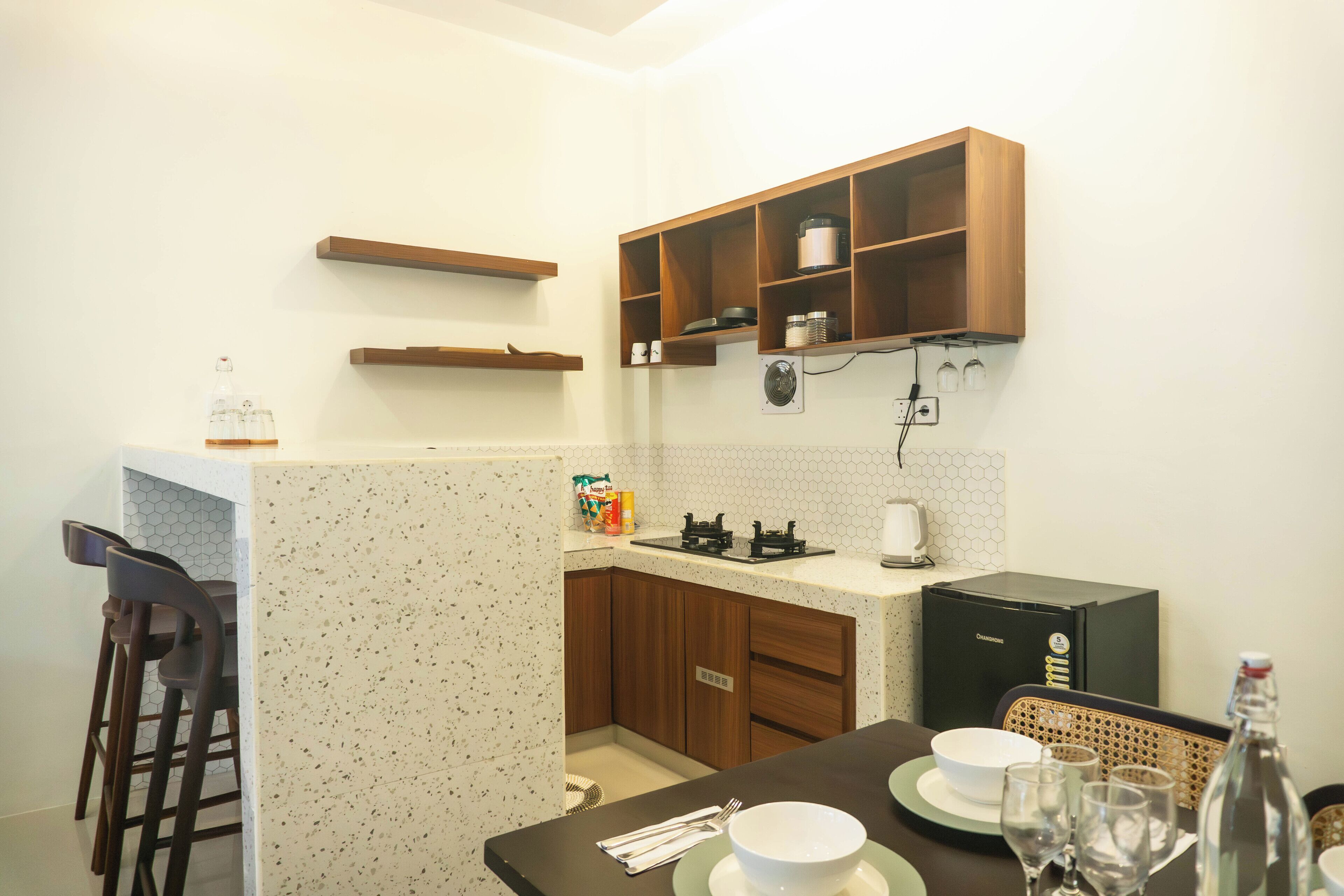 A compact kitchen with wooden cabinets, a countertop, and a dining area with a table set for two.