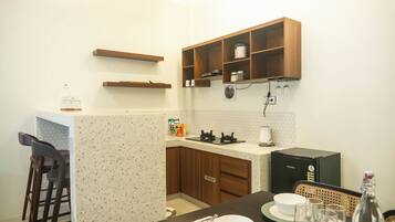 A compact kitchen with wooden cabinets, a countertop, and a dining area with a table set for two.