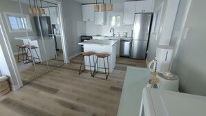 Eine moderne Küche mit weißen Schränken, Edelstahlgeräten und Holzböden.