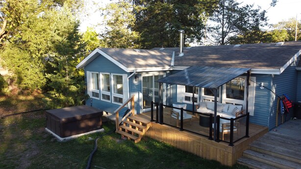 Ein kleines Haus mit überdachter Terrasse, Whirlpool und einer Holzterrasse.