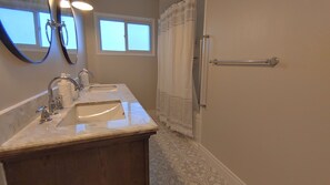 A bathroom with two sinks, a mirror, a towel rack, and a window.