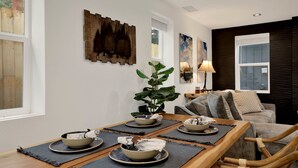 Un comedor con una mesa de madera dispuesta para cuatro personas, rodeada de esteras oscuras.