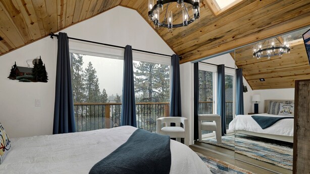 Un dormitorio con una cama grande, vistas al exterior y techo de madera.