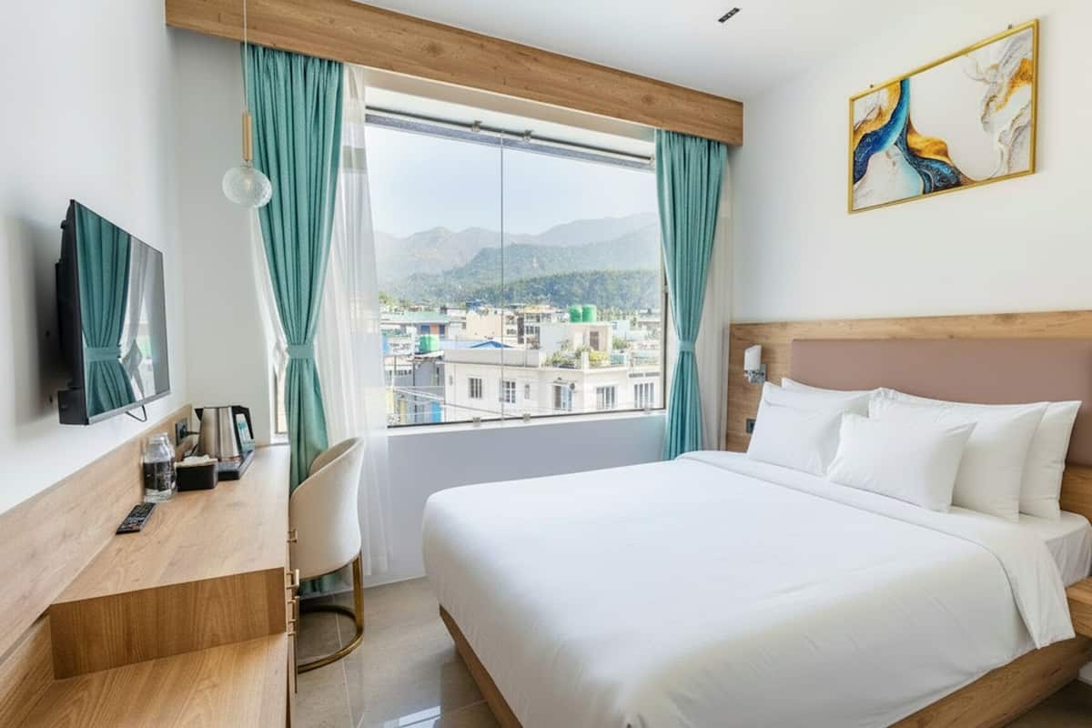 A hotel room with a bed, bedside table, lamp, and a painting.
