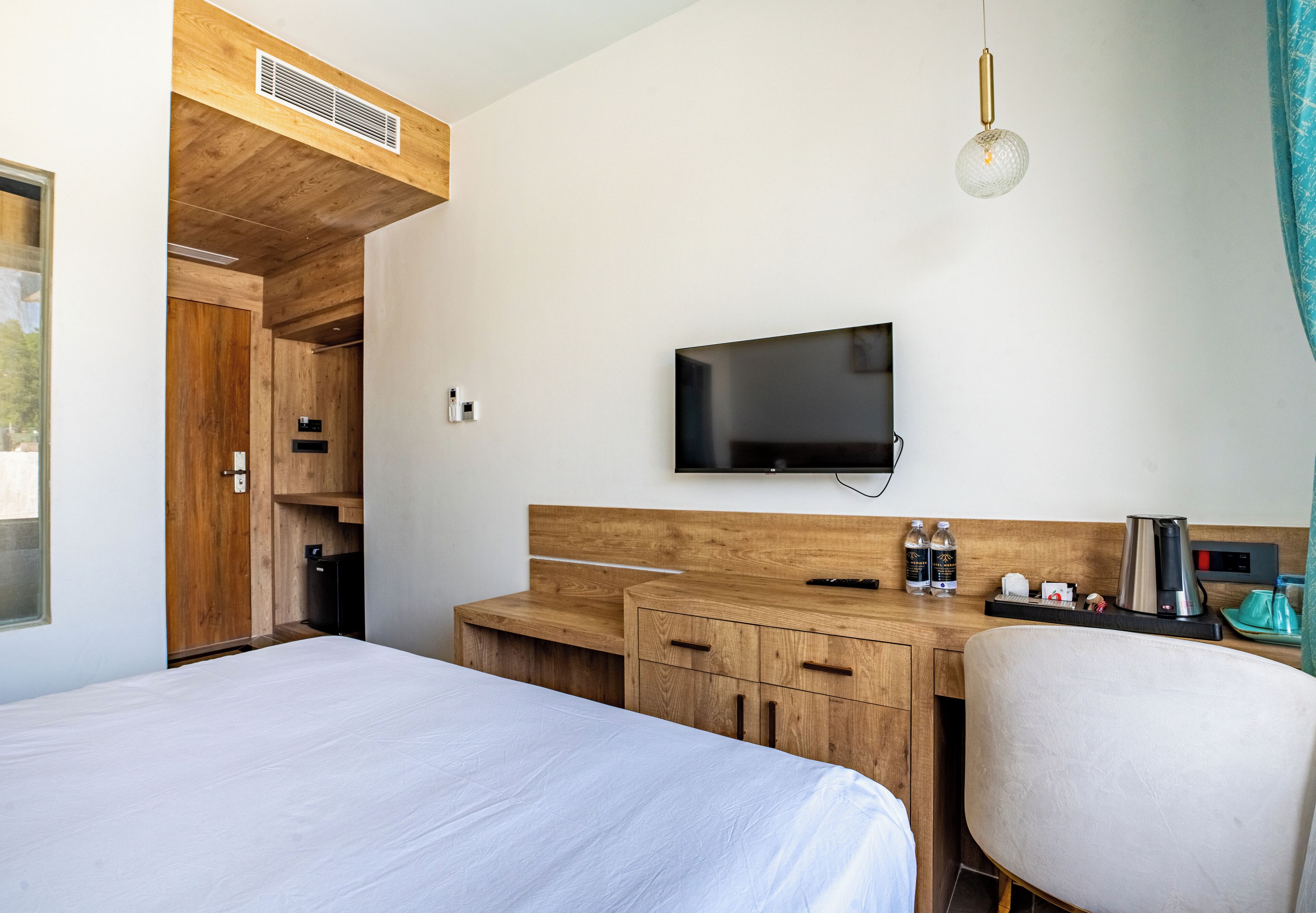 Una habitación de hotel moderna con una cama, un escritorio de madera, un televisor y una silla.