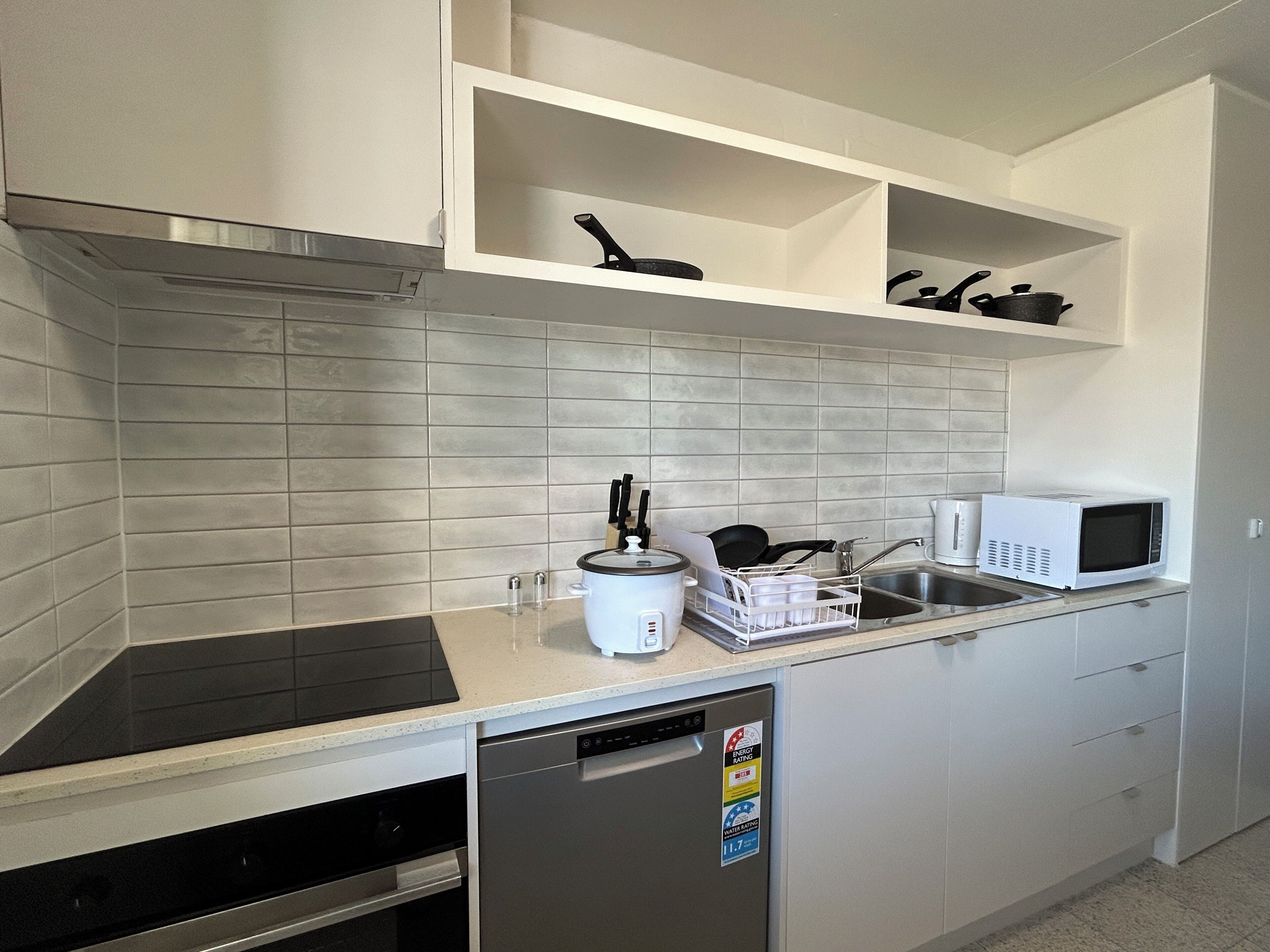 A modern kitchen with a dishwasher, microwave, and a dish rack.
