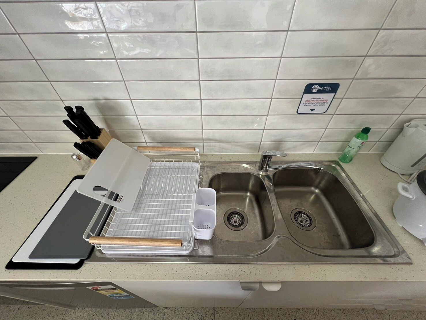 A kitchen with a sink, a cutting board, a knife block, and a dish rack.