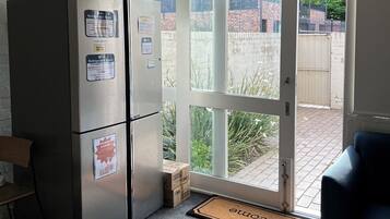 A kitchen with a refrigerator, a door to a patio, and a doormat.