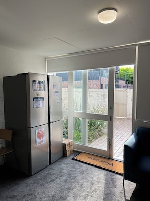 Una cocina con refrigerador, puerta a un patio y felpudo.