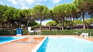 Un espace piscine comprenant deux piscines, un toboggan aquatique et un banc.