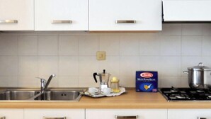 A kitchen with white cabinets, a stainless steel sink, and a stove. - Nice apartment for 6 people with WIFI, A/C, TV, balcony and pets allowed (San Michele Al Tagliamento)
