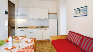 Una habitación compacta con kitchenette, comedor y cama.