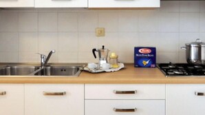 A kitchen with white cabinets, a stainless steel sink, and a stove. - Beautiful apartment for 6 guests with WIFI, A/C, TV, balcony and pets allowed (San Michele Al Tagliamento)