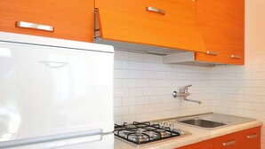 A kitchen with white cabinets, a gas stove, and a sink. - Nice apartment for 6 people with A/C, TV, terrace and pets allowed (San Michele Al Tagliamento)