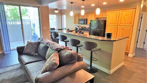 A modern kitchen with a central island, bar stools, and wooden cabinets. - 3-Bedroom Condo in the Heart of the City (Salt Lake City)