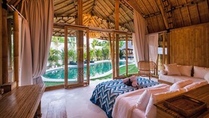 Une pièce spacieuse avec un grand lit, une table en bois et une vue sur une piscine et un espace verdoyant.