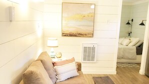 A cozy living room with a beige sofa, a wooden coffee table, and a patterned rug. - Lost River Tiny House, dog-friendly + hot tub (Mathias)