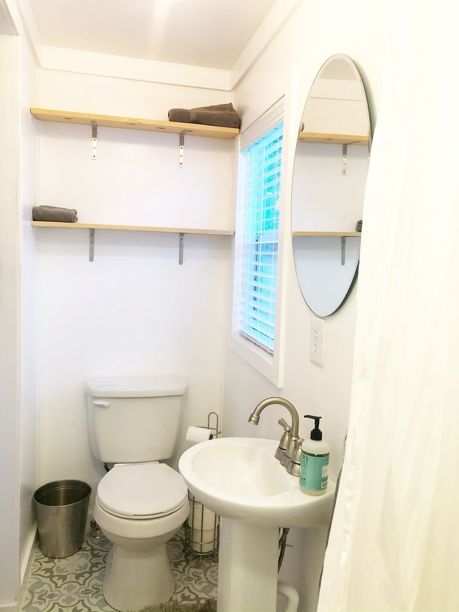 A compact bathroom with a toilet, sink, and two shelves.