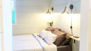 A small, neatly arranged bedroom with a bed, two bedside lamps, and a nightstand. - Lost River Tiny House, dog-friendly + hot tub (Mathias)