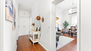 A hallway leading to a living room with a white door, a white console table with books, a mirror, and a vase with flowers. - GuestReady - Charming Porto Retreat for Families (Porto)