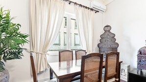 A dining area with a table and chairs, a potted plant, and a decorative item on a stand. - GuestReady - Charming Porto Retreat for Families (Porto)