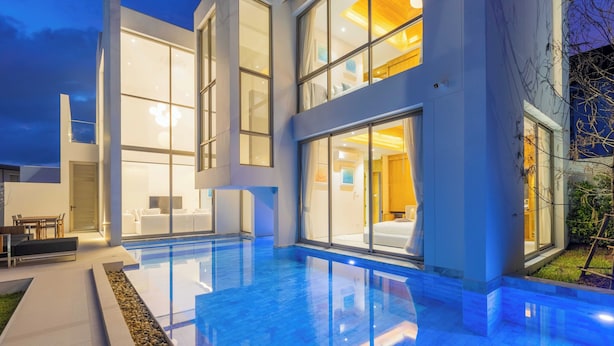 A modern house with a swimming pool, large windows, and a well-lit interior. - Luxpride4  (Si Sunthon)