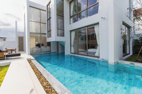 A modern house with a swimming pool, large windows, and a patio area. - Luxpride4 (Si Sunthon)