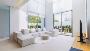 A modern living room with a sectional sofa, a round coffee table, and a flat-screen TV. - Luxpride4  (Si Sunthon)