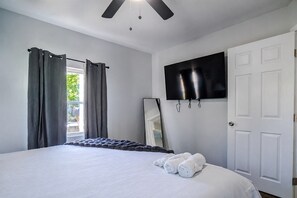 Une chambre d’hôtel avec un lit, un téléviseur à écran plat fixé au mur et une porte.