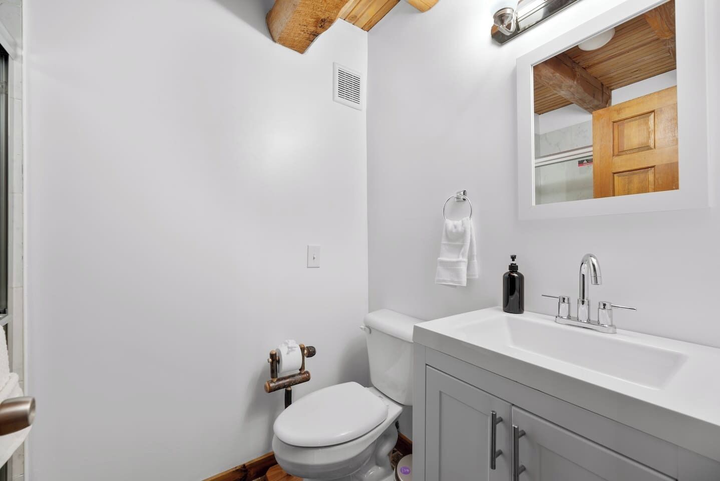 A bathroom with a toilet, sink, and mirror.