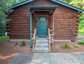 Eine Holzhütte mit einer grünen Tür, einer Veranda und einer Treppe, die zum Eingang führt.