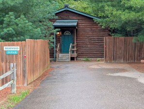 Eine Holzhütte mit einer grünen Tür, einem Holzzaun und einem Schild mit der Aufschrift 'Briarwood 30066'.